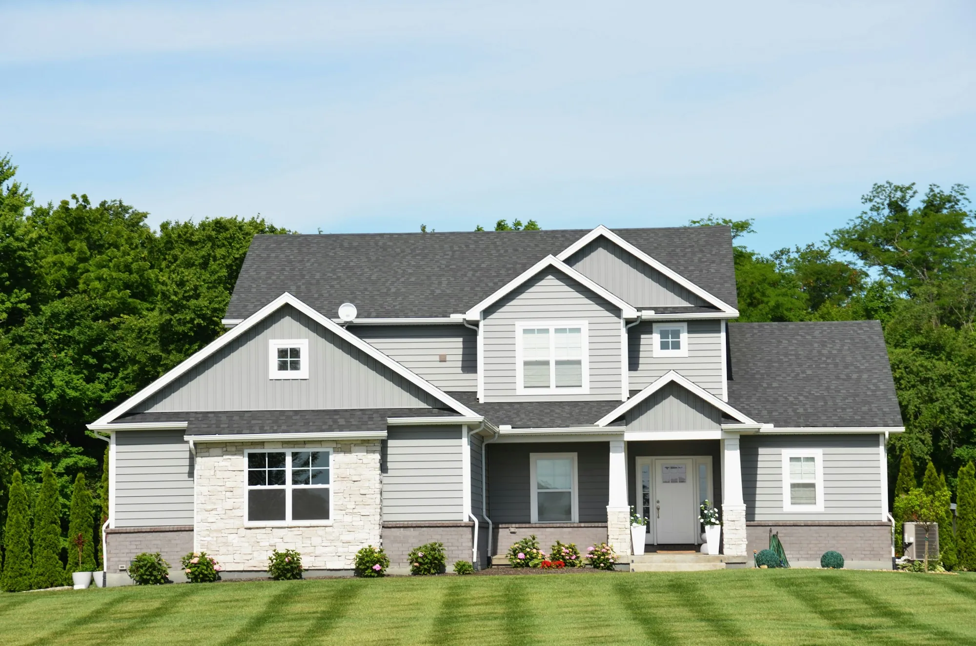 Gray two-story house with a striped lawn