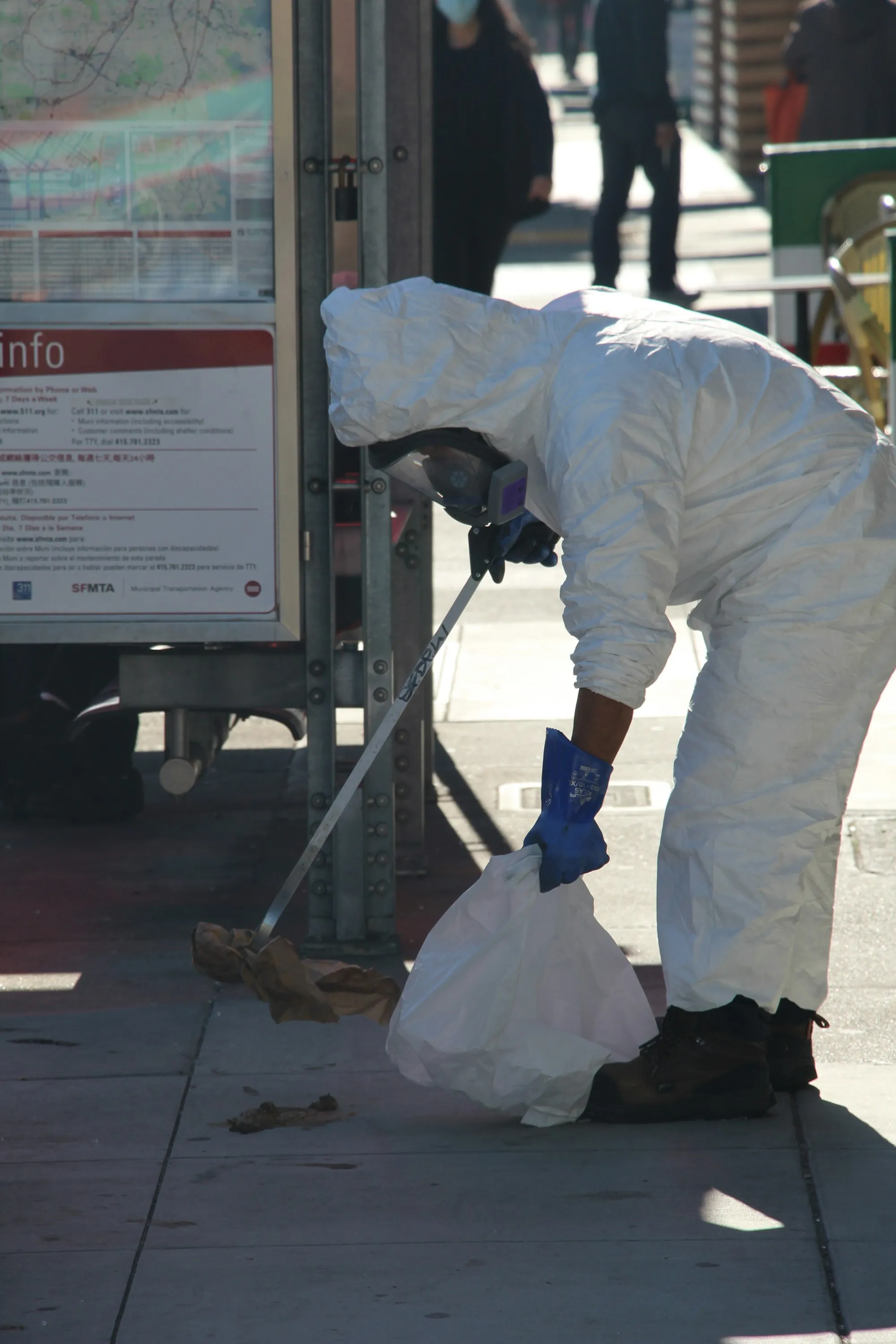 Worker in a protective suit bagging material for disposal